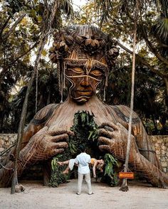 a man standing in front of a giant statue with his hands out to the side