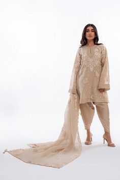 A short beige khaddi corduroy shirt with aari and tilla embroidery is paired with a matching worked organza dupatta. Playful tassel detailing complements the shirt and an embroidered rawsilk shalwar completes the look. Model Height is 5'2 and Shirt Length is 35' Designer Beige Kurta With Cutdana, Beige Cutdana Dupatta, Festive Semi-stitched Beige Sharara, Beige Kurta With Cutdana, Semi-stitched Beige Kurta With Intricate Embroidery, Organza Shirt, Website Features, Organza Dupatta, Silk Shirt