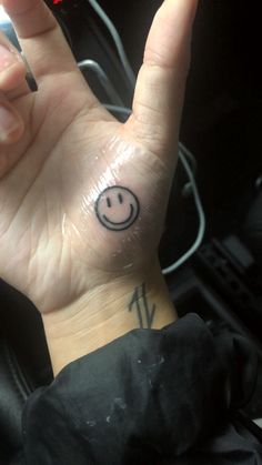 a person's hand with a smiley face tattoo on it