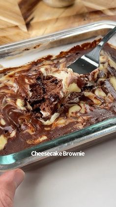 someone is cutting into a chocolate brownie in a pan