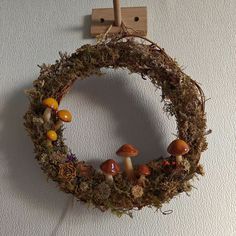 a wreath with mushrooms and moss hanging on a wall