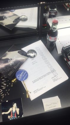 a table with various items on it including a bottle of soda and paper work materials