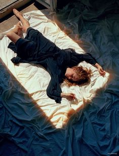 a woman laying on top of a blue sheet