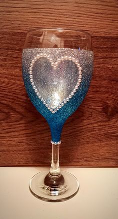 a blue wine glass with a heart painted on the side sitting on a counter top