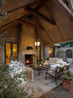 an outdoor living area with couches, table and fire place in the middle of it