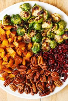 a white plate topped with brussel sprouts, sweet potatoes and pecans