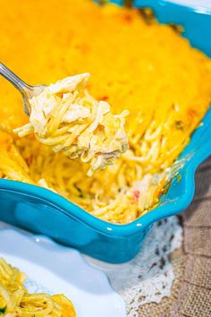 a spoon full of macaroni and cheese being lifted from a blue casserole dish