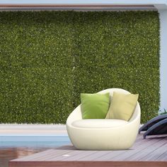 a white chair sitting in front of a wall covered with green plants and pillows next to a swimming pool