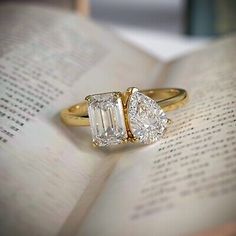 an open book with two engagement rings on top of it and a book in the background