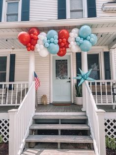 balloons and stars are on the front porch of a house with stairs leading up to it