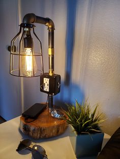 a lamp that is sitting on top of a wooden table next to a potted plant