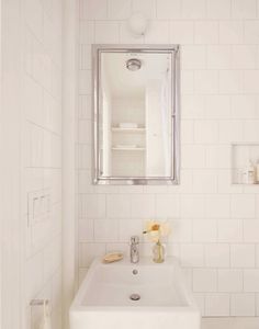 a white bathroom sink sitting under a mirror next to a wall mounted shelf with soap and toothbrushes