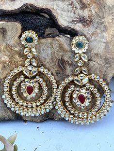 Add a hint of brilliance to your look with these opulent oversized chandbali style earrings with emeralds, ruby and white beads. The spectacular design showcases intricate and captivating detailing. Enhanced with kundan work, green stones add to the captivating beauty of this pair of fine layered kundan chandbali earrings. Pair them with a traditional choker. Details: Handcrafted Metal: Gold Plated Stone: Emeralds, Ruby and Pearls Semi Precious Kundan Dimensions: Length 4 inches / Width 2.5 inch Luxury Bollywood Chandbalis With Tilla Detail, Luxury Kundan Chandelier Chandbali Earrings, Luxury Chandbali Gemstone Earrings, Luxury Bohemian Chandbali Earrings, Luxury Chandbali Cut Dana Jewelry, Chandbali Earrings Totaram Jewelers, Kundan Chandbali, Indian Bridal Jewelry, Bridal Mask