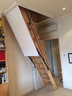 there is a ladder going up to the ceiling in this room with bookshelves