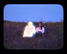 a woman kneeling down in the grass with a light up figure on her chest and head