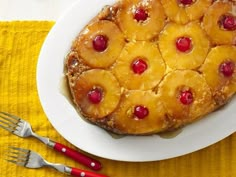 pineapple upside down cake on a white plate with red handled utensils next to it