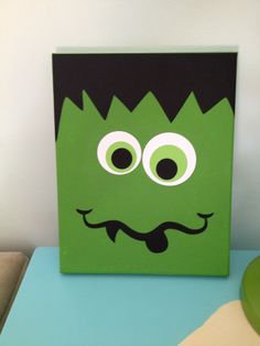 a green box with googly eyes and a mustache on it's face is sitting on a table