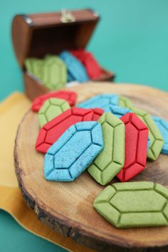 some colorful cookies are on a wooden plate with a suitcase in the backgroud