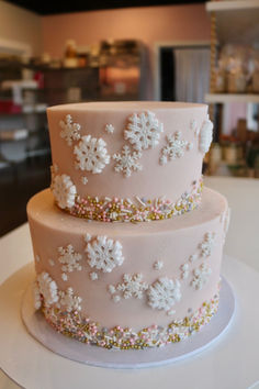 a three tiered cake with white frosting and snowflakes on the side