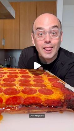 a man with glasses is looking at a large pepperoni pizza on a counter top