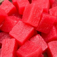 chopped up pieces of watermelon sitting on top of a cutting board