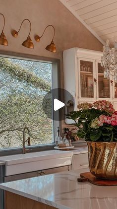 a vase with flowers sitting on top of a kitchen counter next to a sink and window