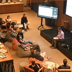 a group of people sitting on bean bag chairs in front of a flat screen tv