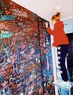 a woman writing on a blackboard with lots of words written all over the wall