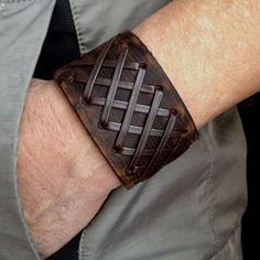 a man's arm wearing a brown leather bracelet with woven squares on the wrist