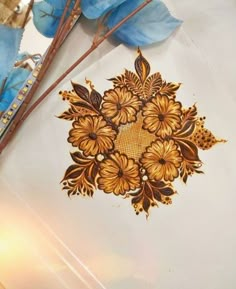 some blue flowers and brown stems on a white tablecloth with gold foilwork designs