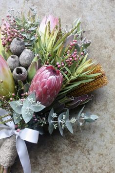 a bunch of flowers that are sitting on the ground with some ribbon around it's neck