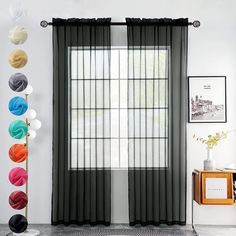 a living room with black curtains and colorful balls hanging on the wall next to it