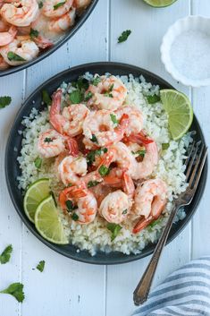 shrimp and rice with lime wedges on the side in a black bowl next to a fork