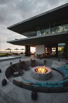 an outdoor fire pit in front of a large building with a balcony and patio area