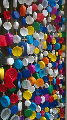 there are many colorful cups and pans hanging on the wall in front of each other