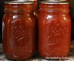 two jars filled with red liquid sitting on top of a counter