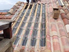 two men are standing on the roof of a building with tiled roofs and tile shingles