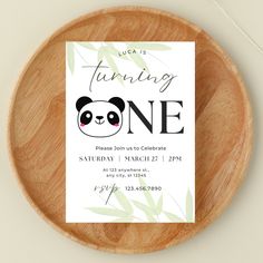 a wooden plate with a card on it that says, i was turning one please join us to celebrate