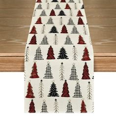 a white table runner with red and black christmas trees on it, sitting next to a wooden