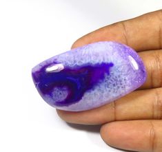 a hand holding a purple and blue object in it's palm