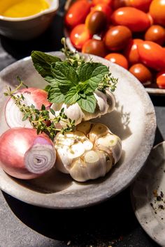 garlic, tomatoes, and other vegetables on a plate next to some sauce in a bowl