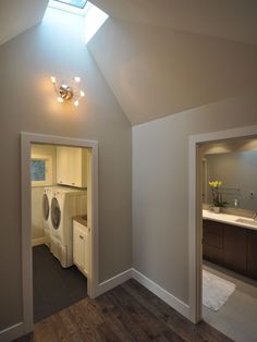 an attic bathroom with skylight and washer dryer in the corner, along with wood flooring