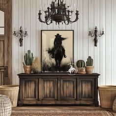 a living room filled with furniture and a painting on top of a wooden cabinet next to a chandelier