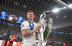 a man holding a soccer trophy in front of a net