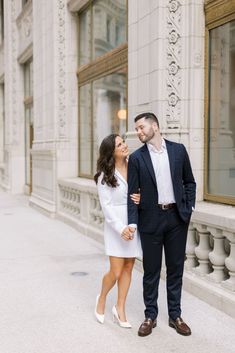 a man and woman standing next to each other in front of a building