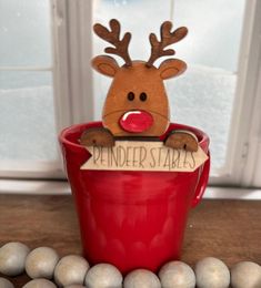 a reindeer head sticking out of a red cup on top of some white and gray balls