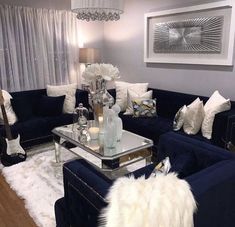 a living room filled with blue couches and white fur rugs on top of a hard wood floor