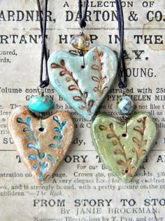 three heart shaped ceramic pendants sitting on top of a piece of paper