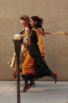 two women are walking down the sidewalk near a parking meter