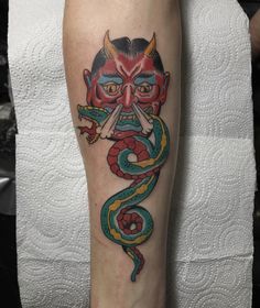 a man with a tattoo on his leg has a snake and demon face tattooed on it